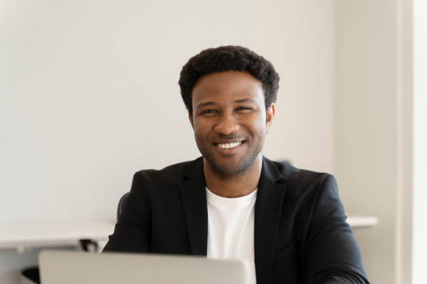 Portrait of a cheerful businessman smiling while working on his laptop, enjoying a productive day at the office